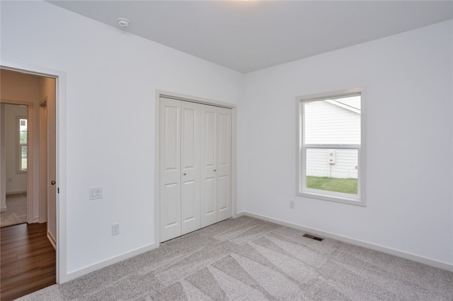 unfurnished bedroom featuring light carpet and a closet