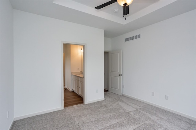 unfurnished bedroom with ceiling fan, light colored carpet, sink, and ensuite bath