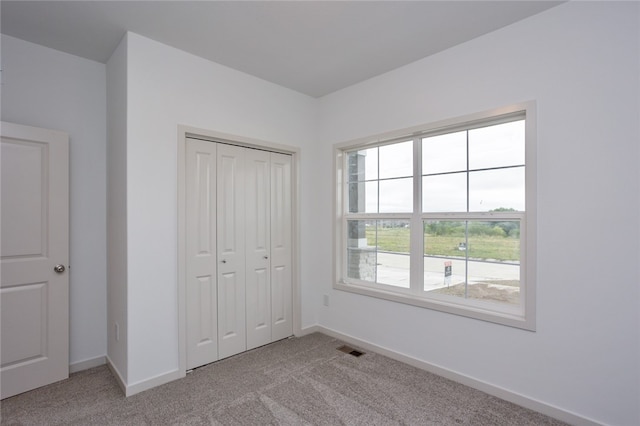 unfurnished bedroom with light colored carpet and a closet