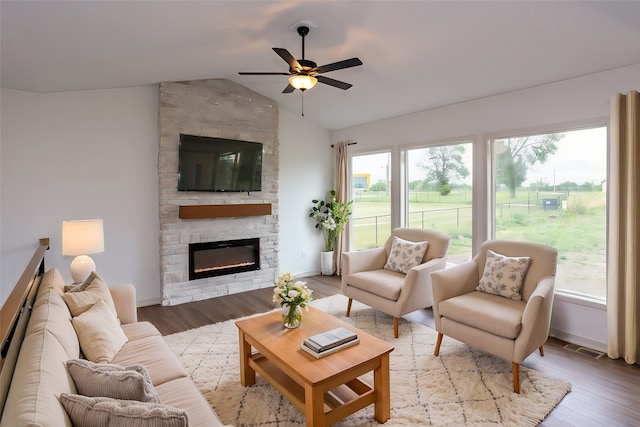 living room featuring a stone fireplace, plenty of natural light, hardwood / wood-style floors, and lofted ceiling