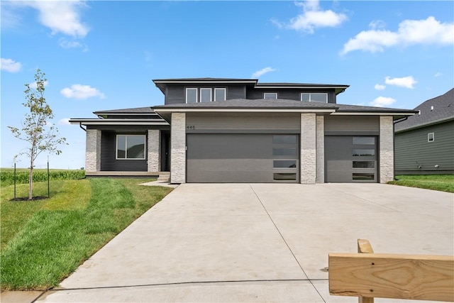 prairie-style home with a garage, driveway, a front lawn, and brick siding