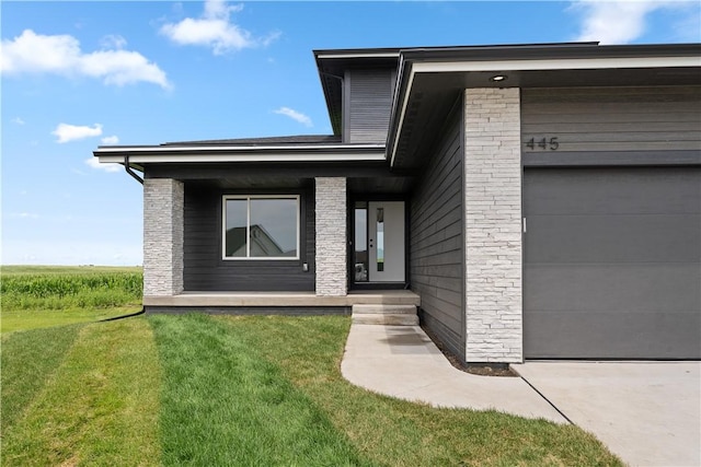 view of exterior entry featuring a yard and a garage