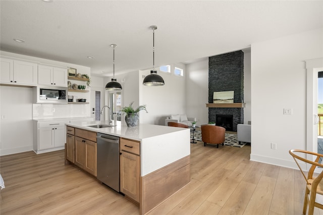 kitchen with built in microwave, dishwasher, sink, white cabinets, and a center island with sink