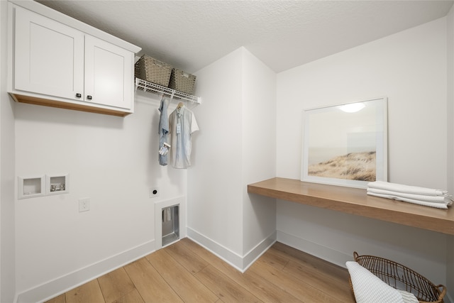 washroom featuring hookup for a washing machine, electric dryer hookup, cabinets, and light hardwood / wood-style floors