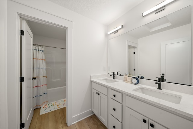 bathroom with vanity, hardwood / wood-style floors, a textured ceiling, and shower / bath combo