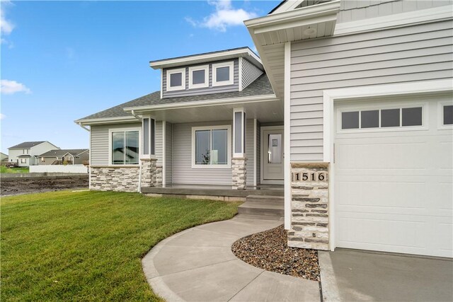 view of exterior entry with a garage and a yard