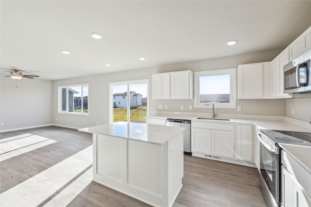 2009 White Oak Ln, Granger, IA 50109 - kitchen with appliances with stainless steel finishes, a sink, a center island, light wood-type flooring, and recessed lighting