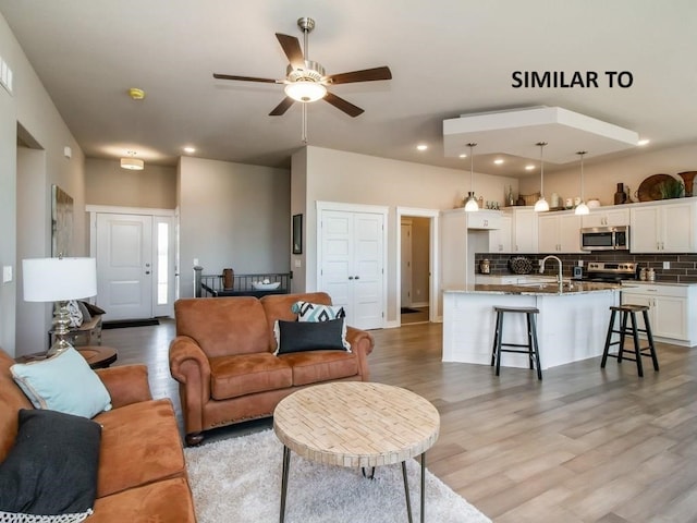 living room with sink, ceiling fan, and light hardwood / wood-style floors