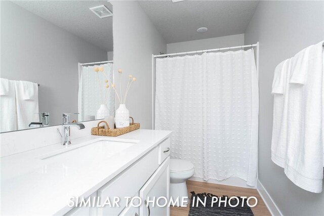 bathroom featuring vanity, a textured ceiling, toilet, and hardwood / wood-style floors