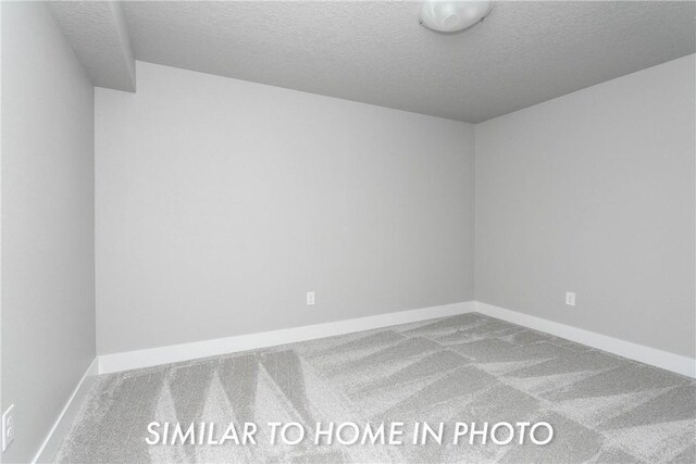 carpeted spare room featuring a textured ceiling