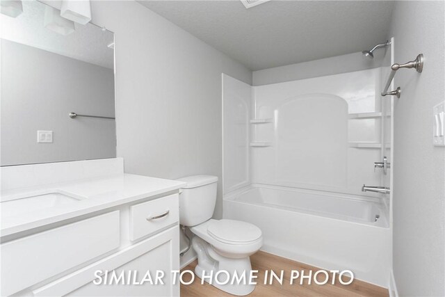 full bathroom with a textured ceiling, tub / shower combination, toilet, vanity, and hardwood / wood-style flooring