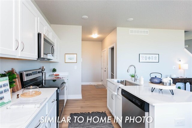 kitchen featuring appliances with stainless steel finishes, light hardwood / wood-style flooring, white cabinets, and sink