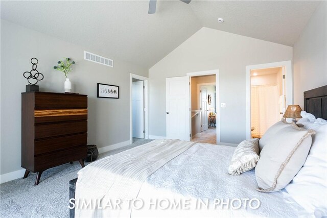 carpeted bedroom with ensuite bath, ceiling fan, and high vaulted ceiling