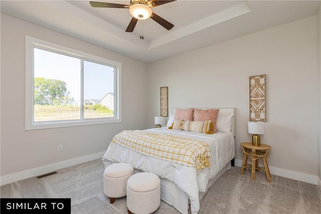 bedroom with visible vents, a tray ceiling, baseboards, and carpet flooring