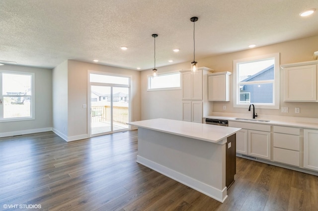 kitchen featuring a center island, dark wood-style flooring, light countertops, and a sink