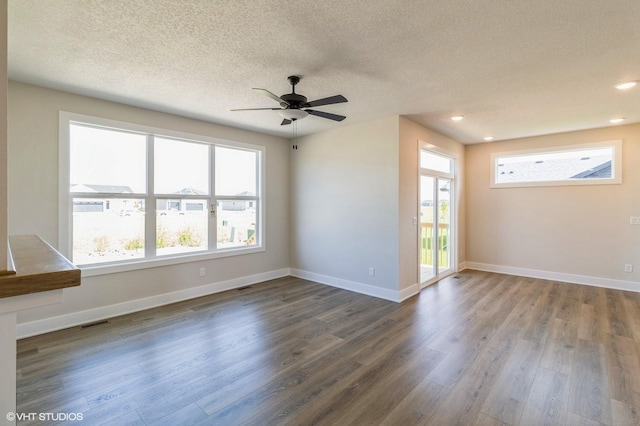 unfurnished room featuring dark wood-style floors, a textured ceiling, visible vents, and baseboards