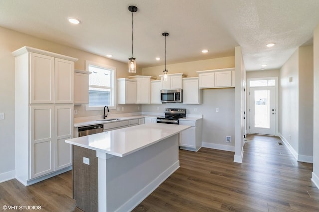 kitchen with stainless steel appliances, dark wood-type flooring, a sink, and white cabinetry