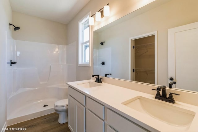 bathroom featuring wood finished floors, a sink, toilet, and walk in shower