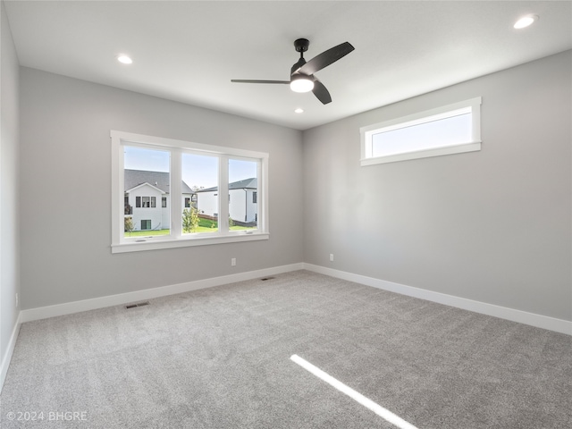 empty room with a wealth of natural light, ceiling fan, and carpet floors