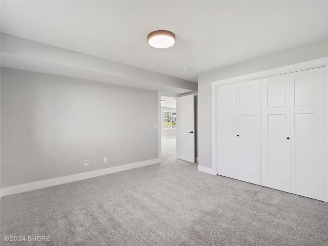 unfurnished bedroom with a closet and light colored carpet