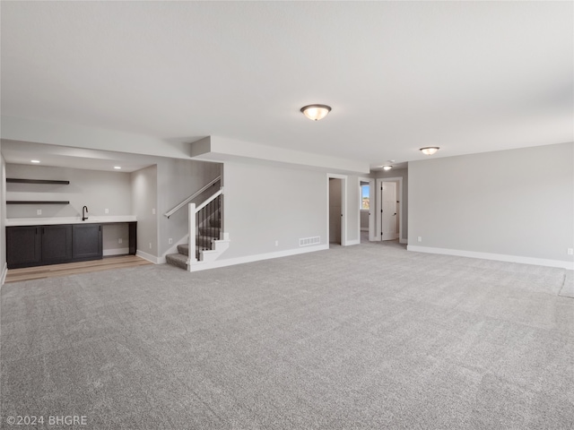 unfurnished living room with sink and carpet floors