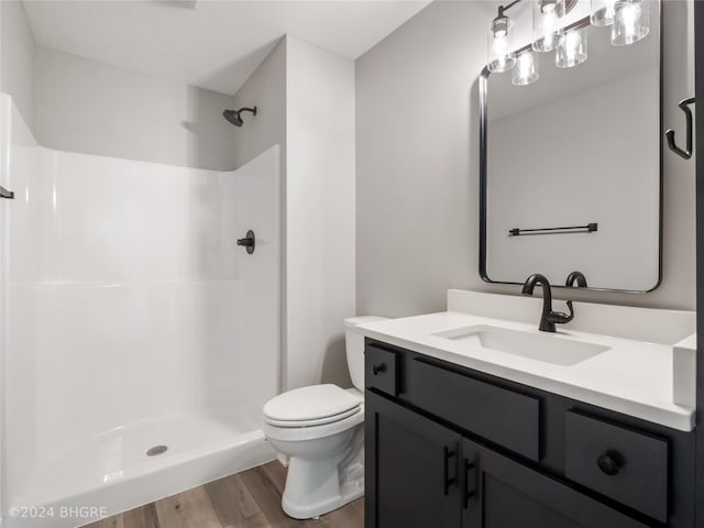 bathroom with walk in shower, vanity, hardwood / wood-style flooring, and toilet