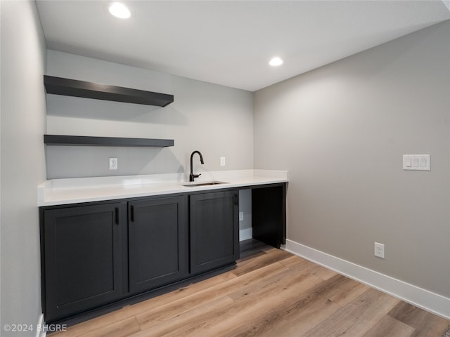 bar with sink and light hardwood / wood-style floors