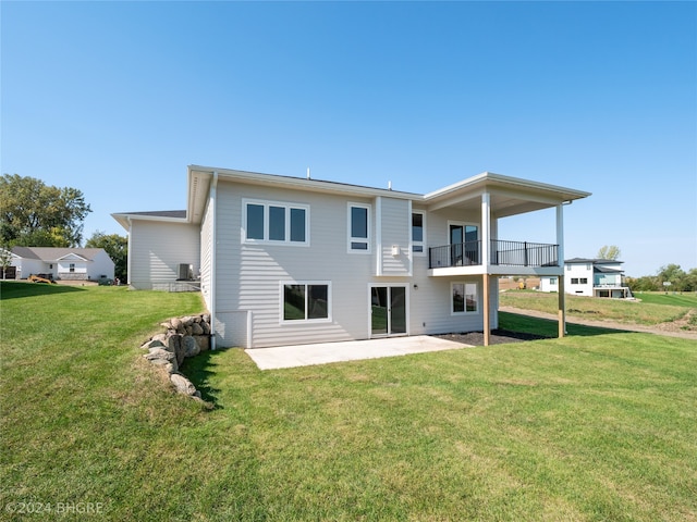 back of property with a balcony, a lawn, and a patio area