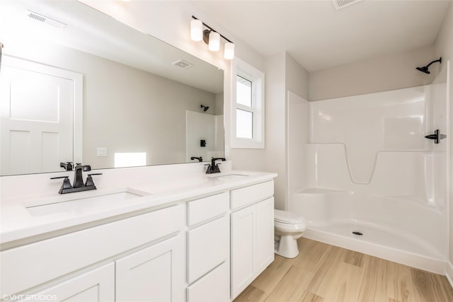 bathroom featuring walk in shower, vanity, toilet, and wood-type flooring