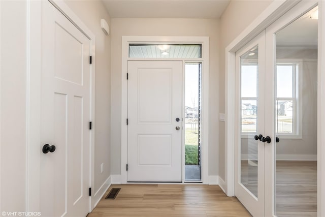 foyer with french doors and light hardwood / wood-style flooring