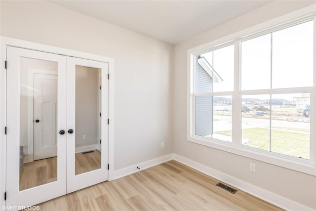 unfurnished room with light hardwood / wood-style floors and french doors