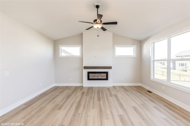 unfurnished living room featuring plenty of natural light, a large fireplace, and light hardwood / wood-style flooring