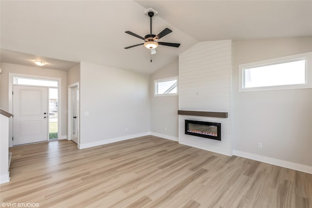 unfurnished living room with ceiling fan, a fireplace, lofted ceiling, and light wood-type flooring