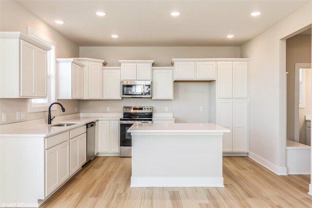 kitchen featuring white cabinets, sink, light hardwood / wood-style floors, appliances with stainless steel finishes, and a kitchen island