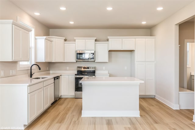 kitchen with white cabinetry, sink, a center island, stainless steel appliances, and light hardwood / wood-style flooring