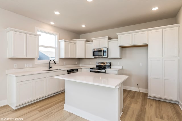 kitchen featuring appliances with stainless steel finishes, a kitchen island, sink, light hardwood / wood-style floors, and white cabinetry