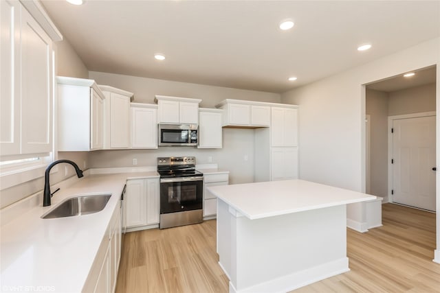 kitchen with stainless steel appliances, a kitchen island, sink, and white cabinets