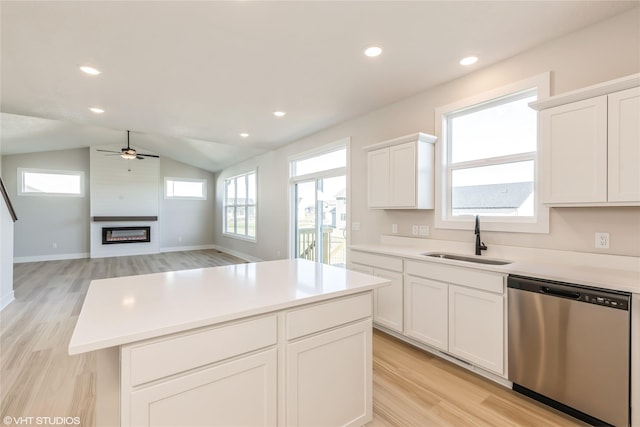 kitchen featuring light wood-type flooring, stainless steel dishwasher, sink, a kitchen island, and lofted ceiling