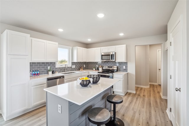 kitchen featuring a breakfast bar, stainless steel appliances, a center island, light hardwood / wood-style floors, and white cabinetry