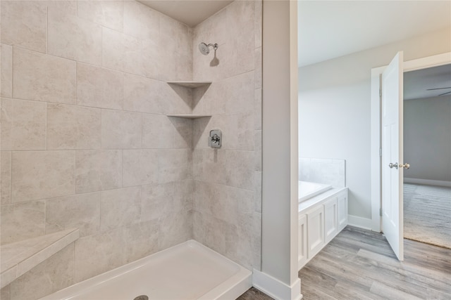 bathroom with tiled shower and hardwood / wood-style flooring