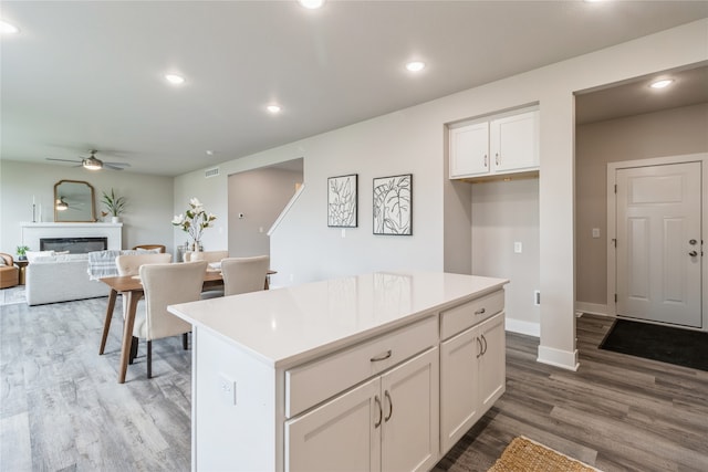 kitchen with white cabinetry, hardwood / wood-style flooring, ceiling fan, and a kitchen island