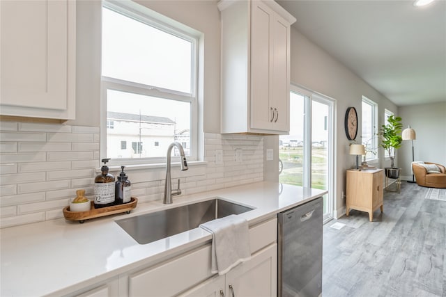 kitchen featuring tasteful backsplash, dishwasher, sink, white cabinetry, and light hardwood / wood-style floors