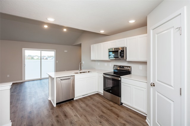 kitchen featuring appliances with stainless steel finishes, kitchen peninsula, white cabinets, and sink