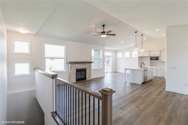 unfurnished living room featuring lofted ceiling, sink, hardwood / wood-style flooring, ceiling fan, and a fireplace