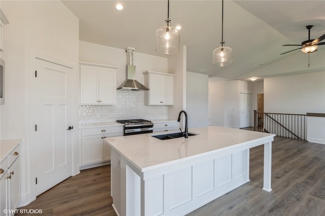 kitchen featuring white cabinets, a kitchen island with sink, sink, and stainless steel gas range