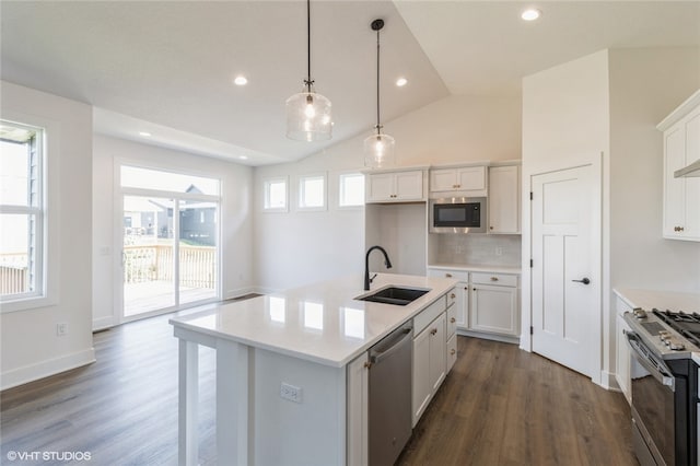 kitchen with sink, stainless steel appliances, vaulted ceiling, white cabinets, and a center island with sink