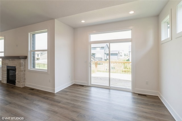 unfurnished living room with a stone fireplace and wood-type flooring