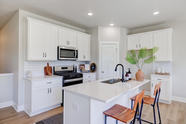 kitchen featuring white cabinets, sink, appliances with stainless steel finishes, and an island with sink