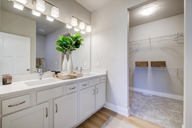 bathroom featuring wood-type flooring, vanity, and a textured ceiling