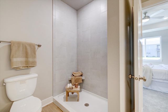 bathroom with ceiling fan, toilet, and tiled shower